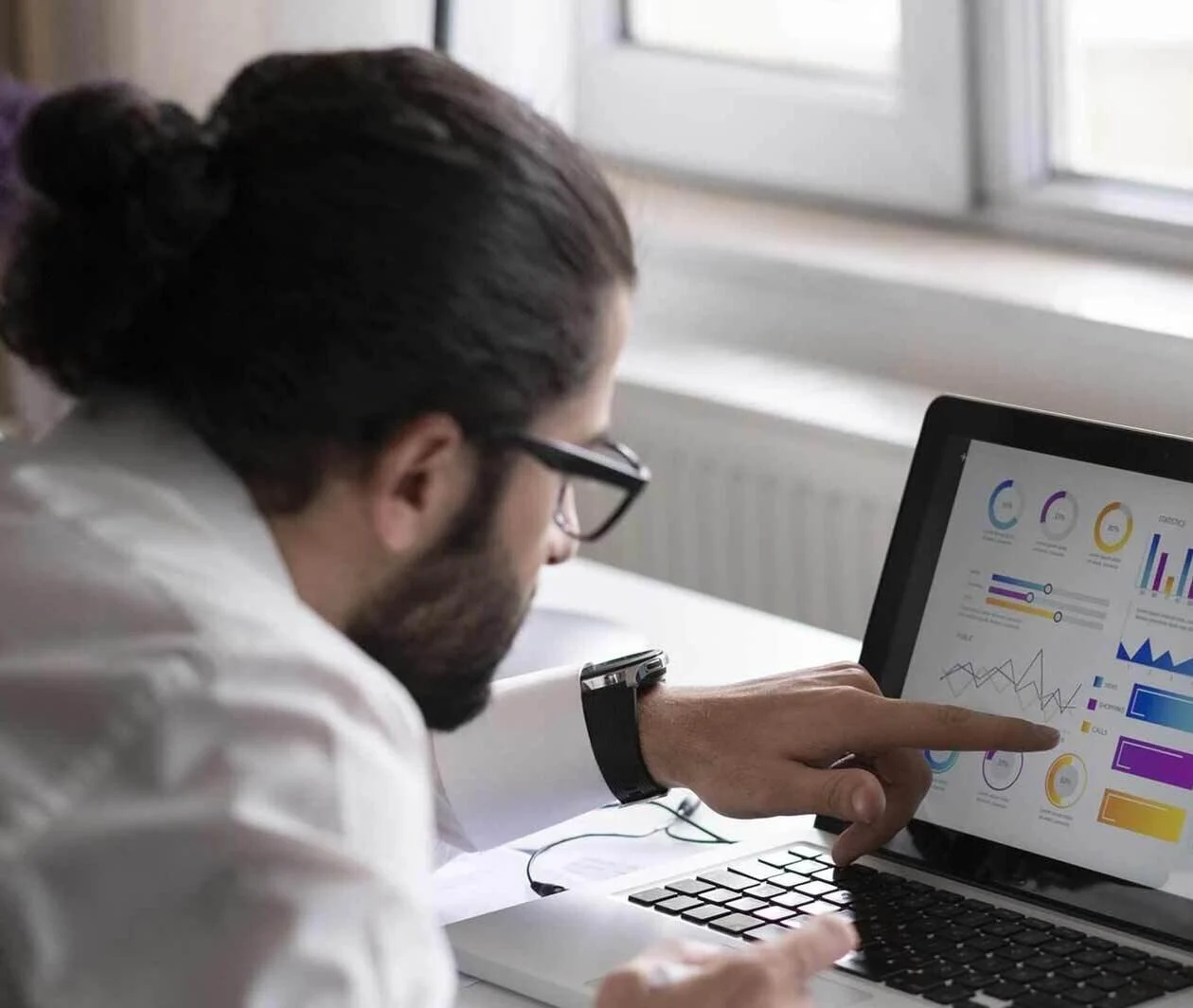 Men with glasses looking at a computer screen and pointing at a graph