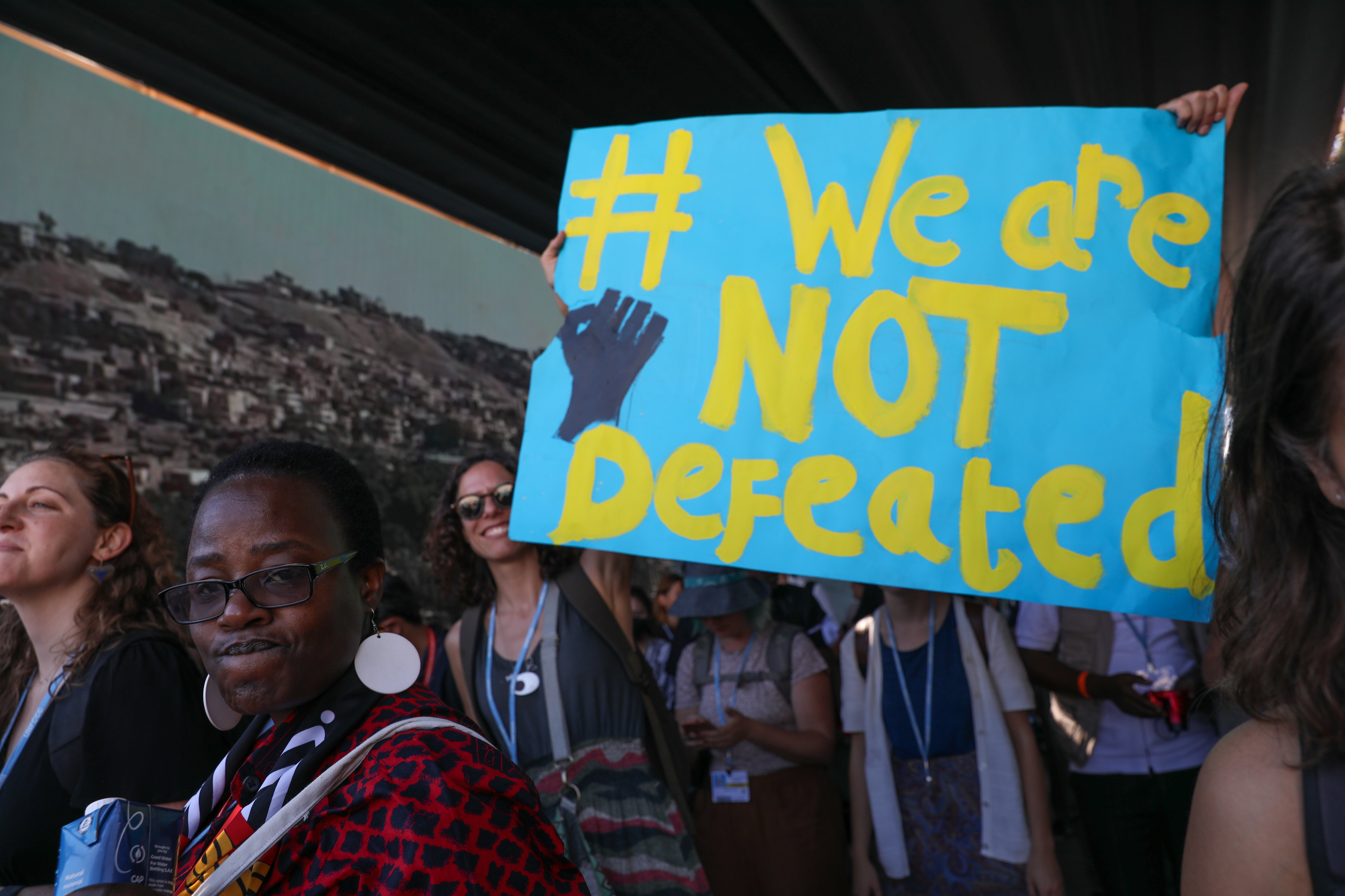 protest with a banner saying 'we are not defeated'