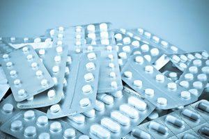 A pile of various pill packets, representing drugs and medicines