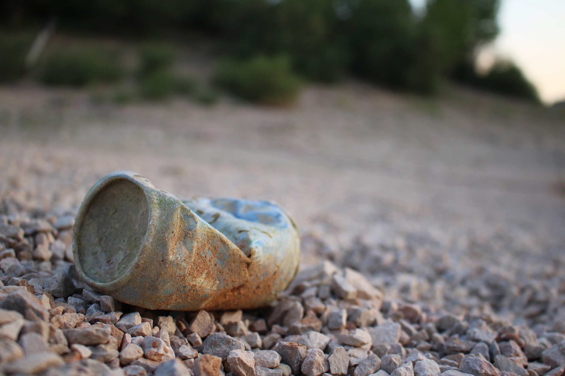 An empty finished can lying on a stoned road