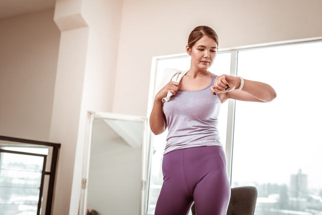 A woman in a gym looking at her watch.