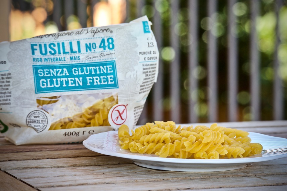 Opened bag of gluten free pasta on a picnic table, along with some pasta on a plate