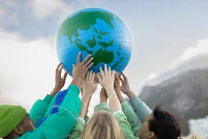 Photograph of a group of young people holding a globe above their heads