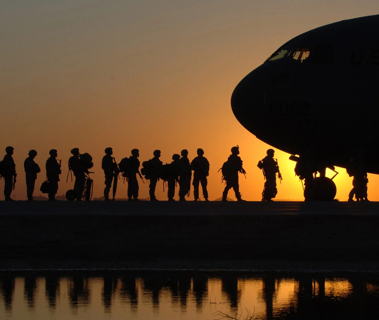 US army soldiers boarding a plane at sunrise