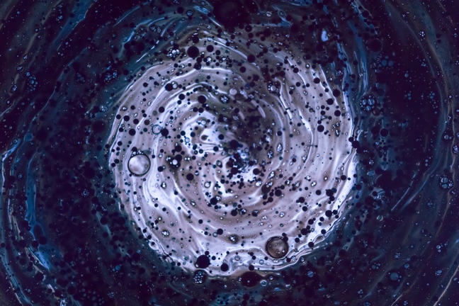 Close-up of water with rippling ring radiating outward from a centre that is light purple and concentrated with chemicals