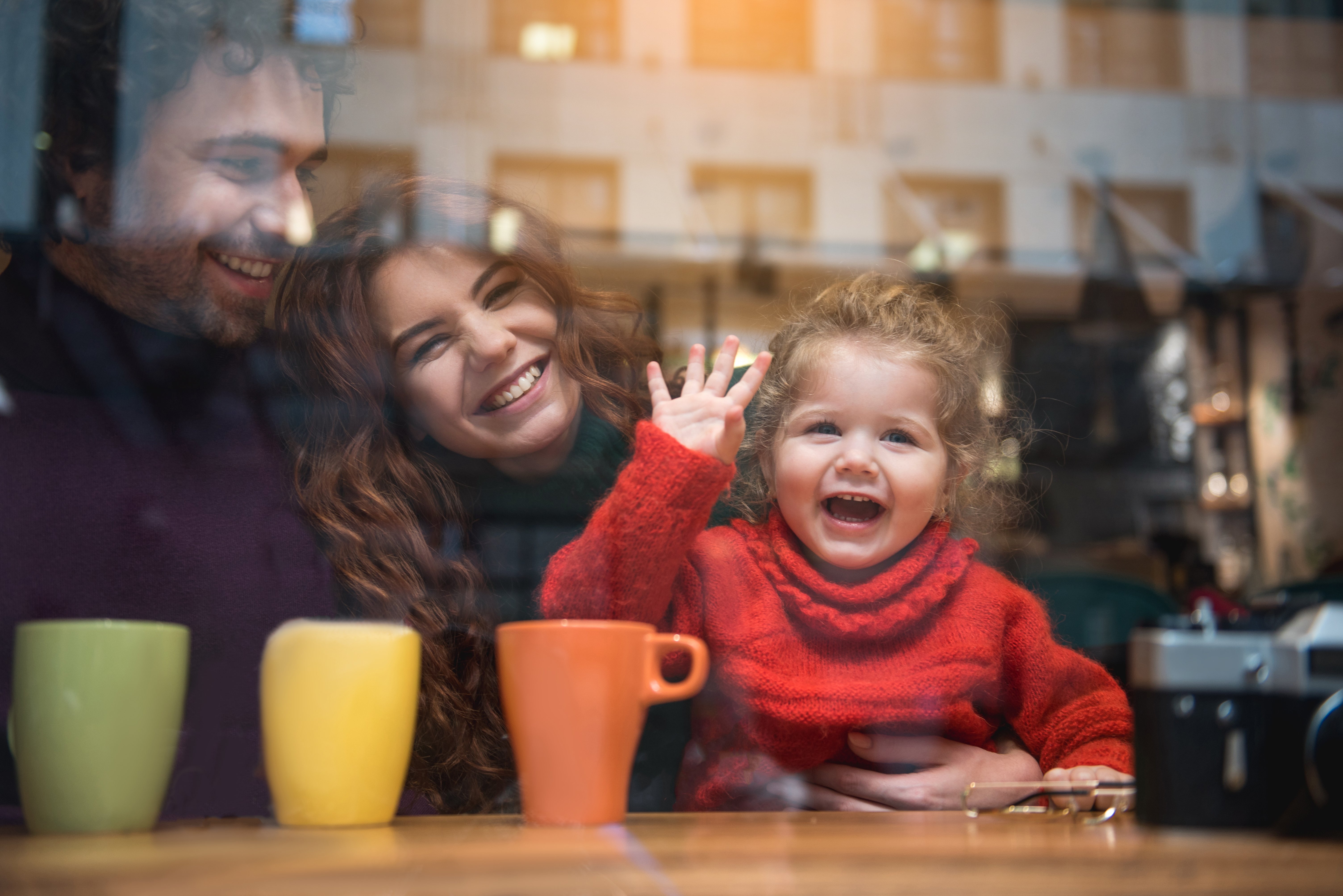 A man, woman and girl saying goodbye in a coffee shop.