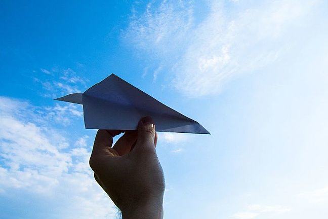 Paper plane being held up in the air