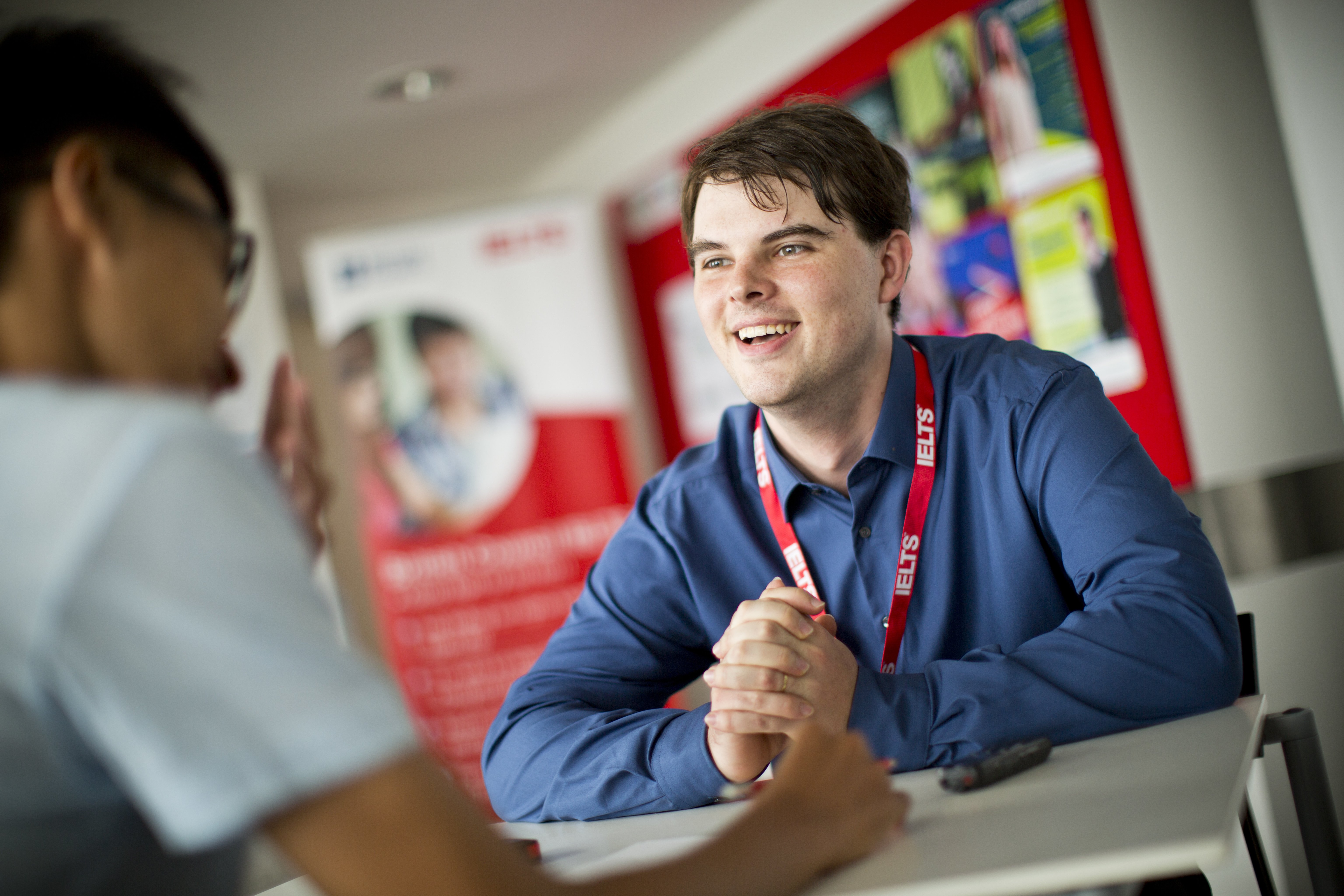 A smiling interviewer talks to an IELTS candidate