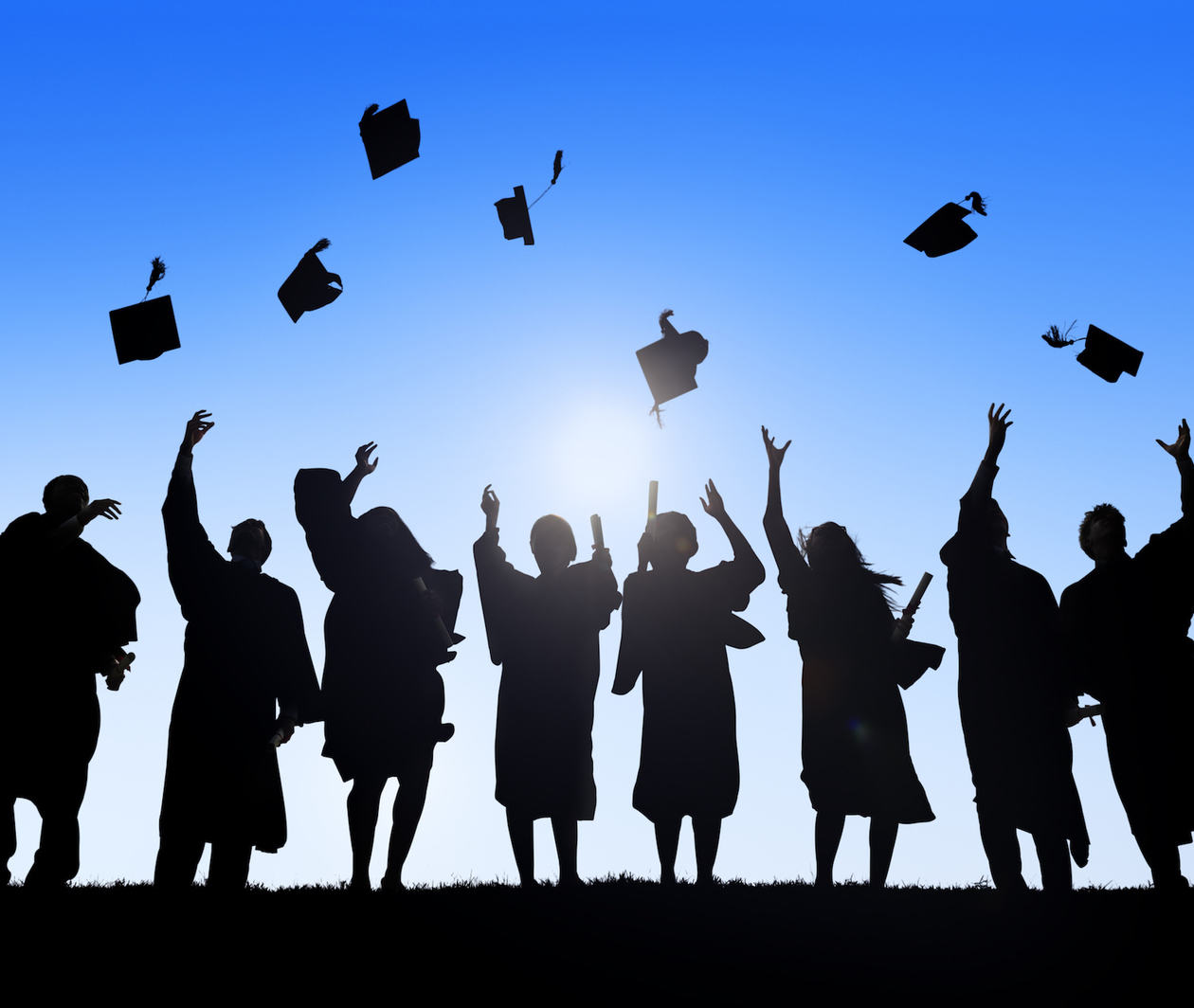 Group of postgraduate students in academic dress celebrating on graduation day.