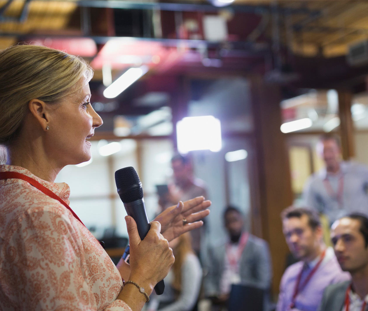 Businesswoman with microphone speaking to conference audience