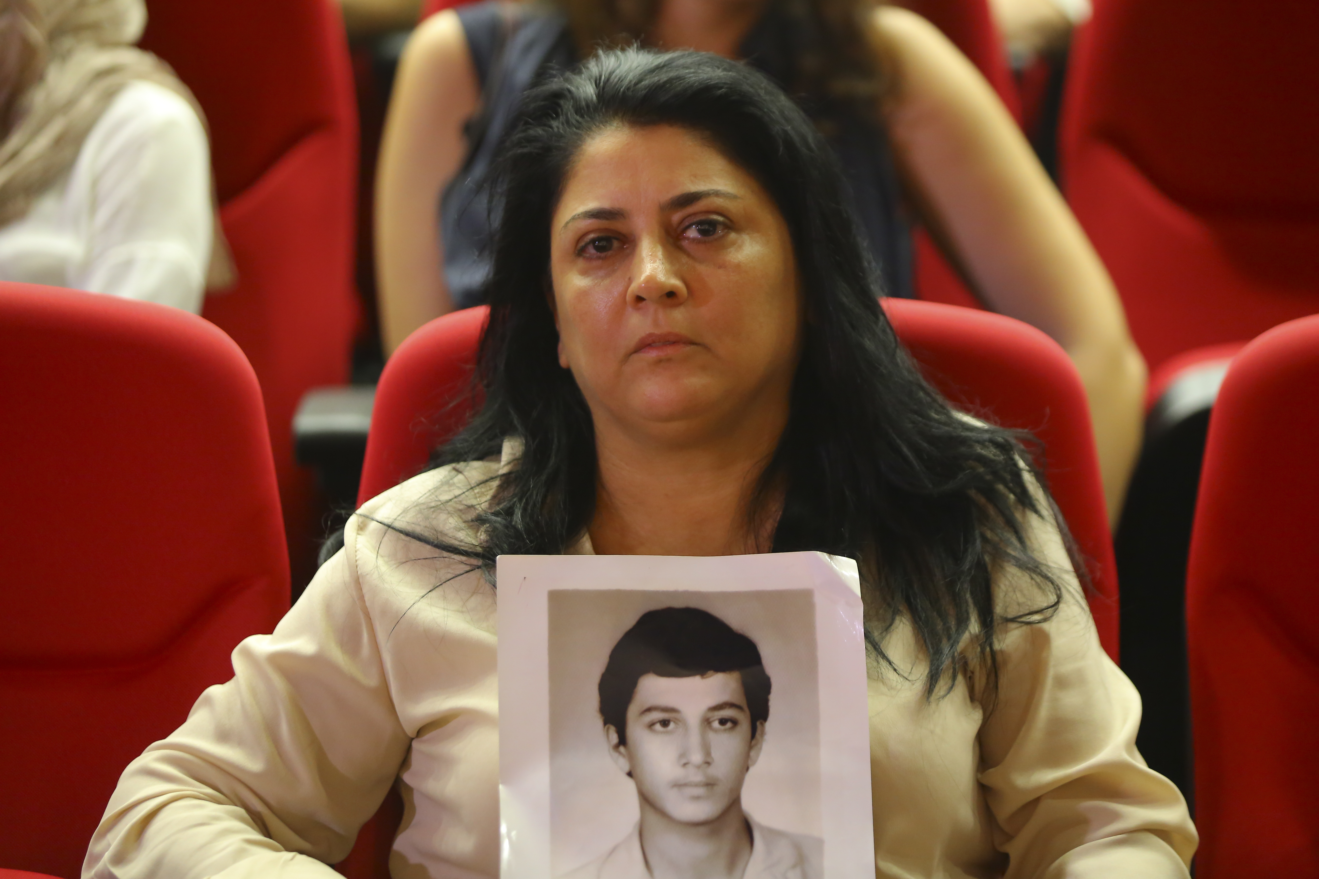 A woman holds up a photograph of her missing adult son.