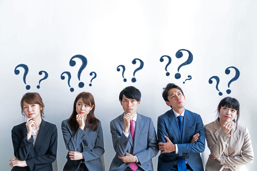 A group of 3 women and 2 men standing in a row, facing forward in a thoughtful pose with question marks hovering above their heads.