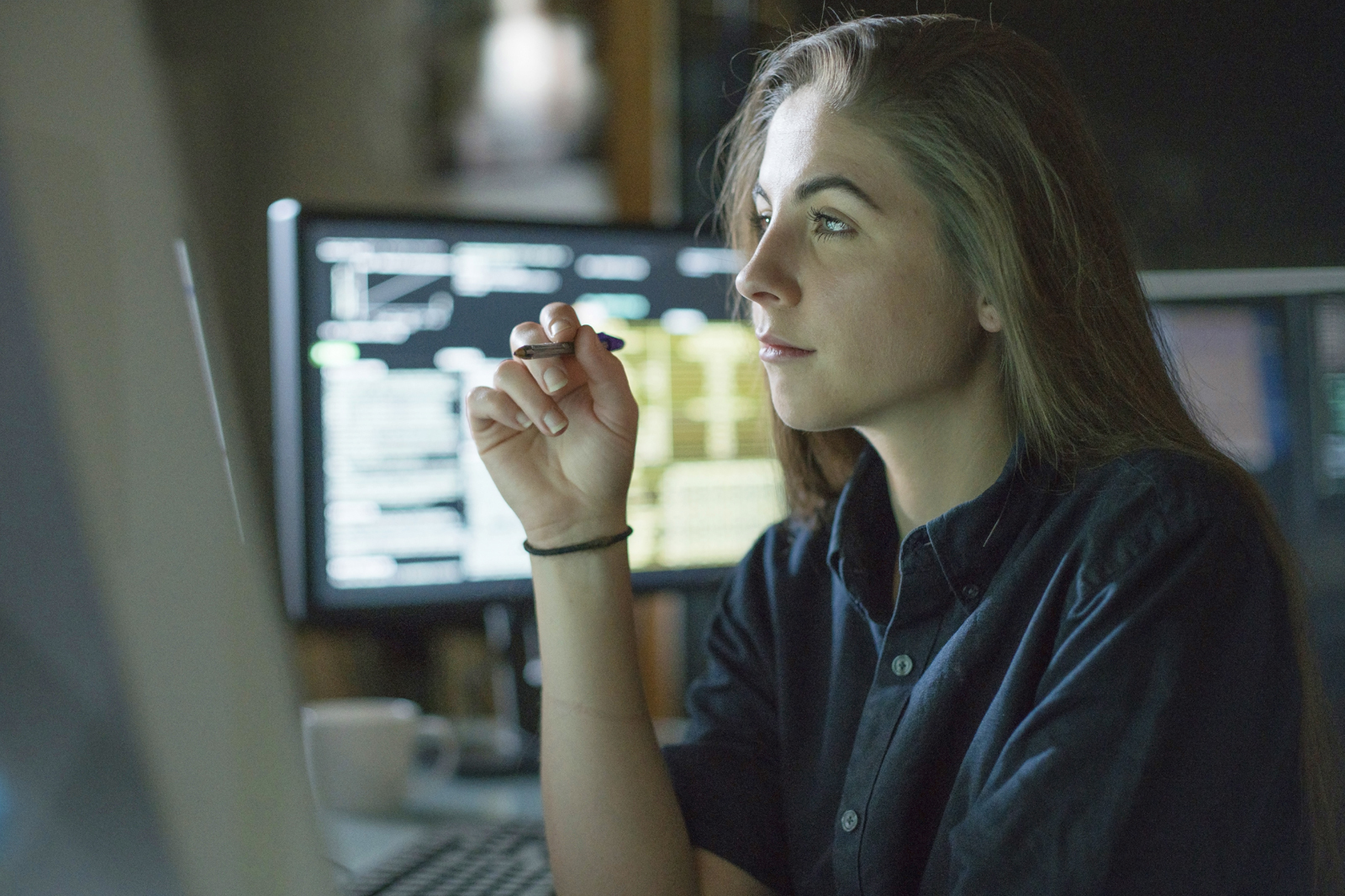 Girl hold a pen and purposefully looks at computer screen