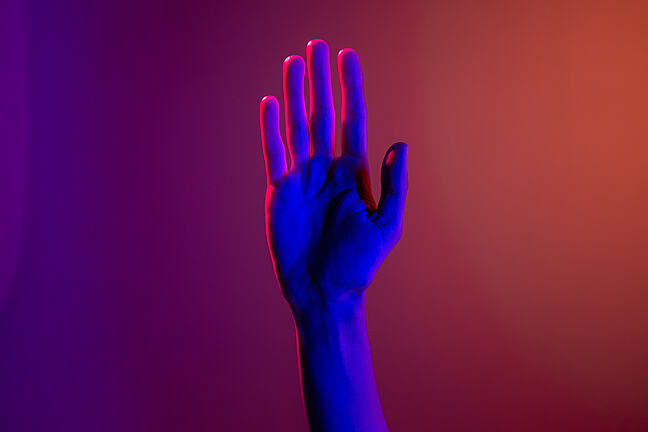 Image of a waving hand on a background of sunset colours.