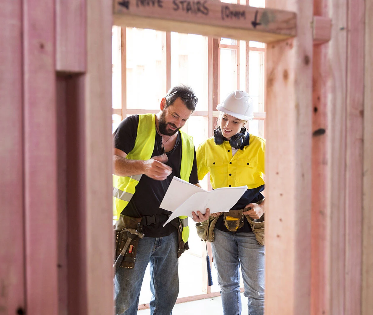 Male and female construction workers discuss a building plan