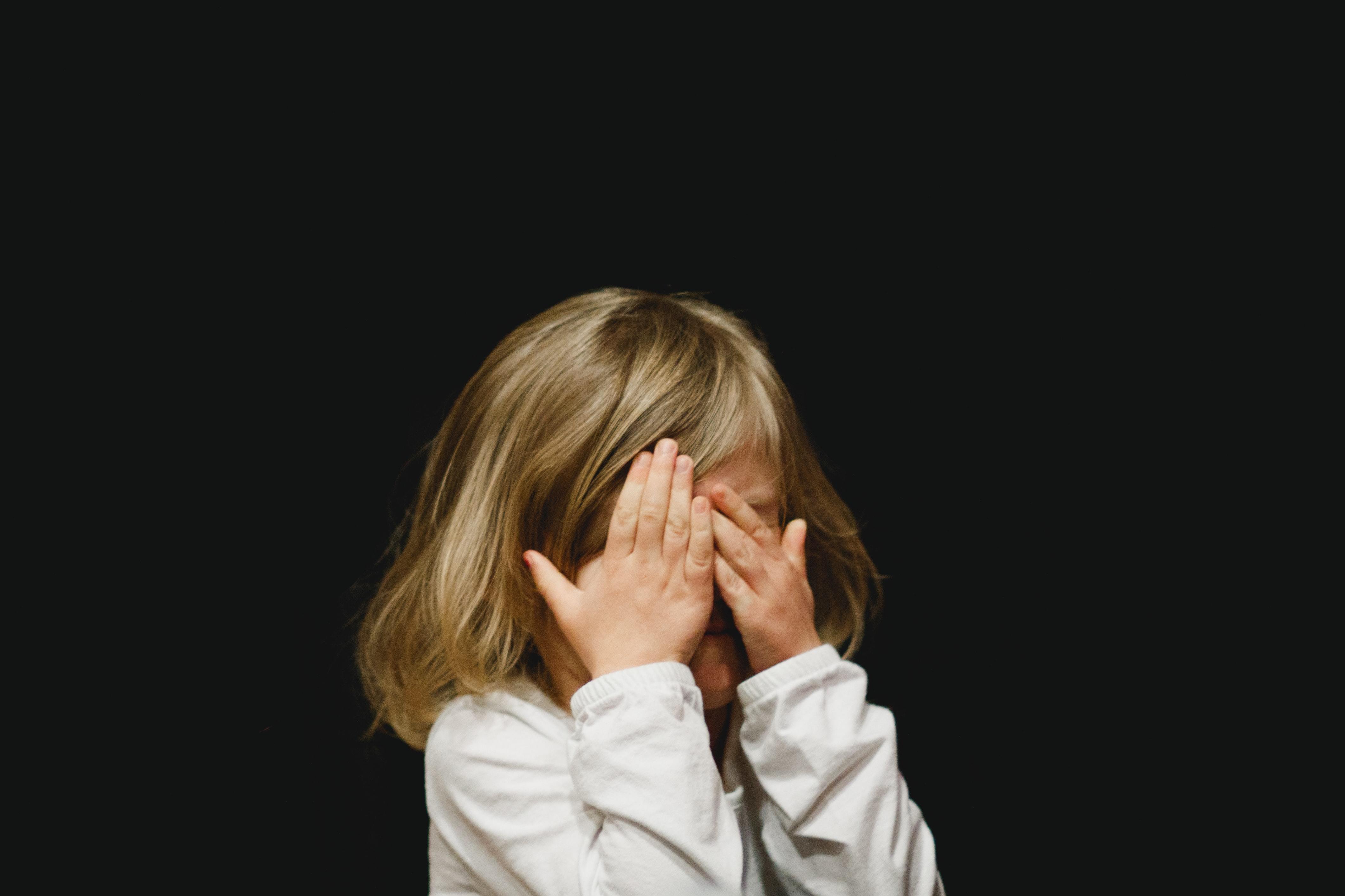 A young girl covering her face with her hands