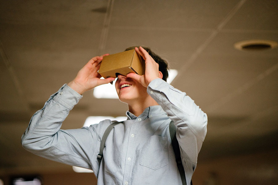 Man in grey dress shirt using brown cardboard VR glasses