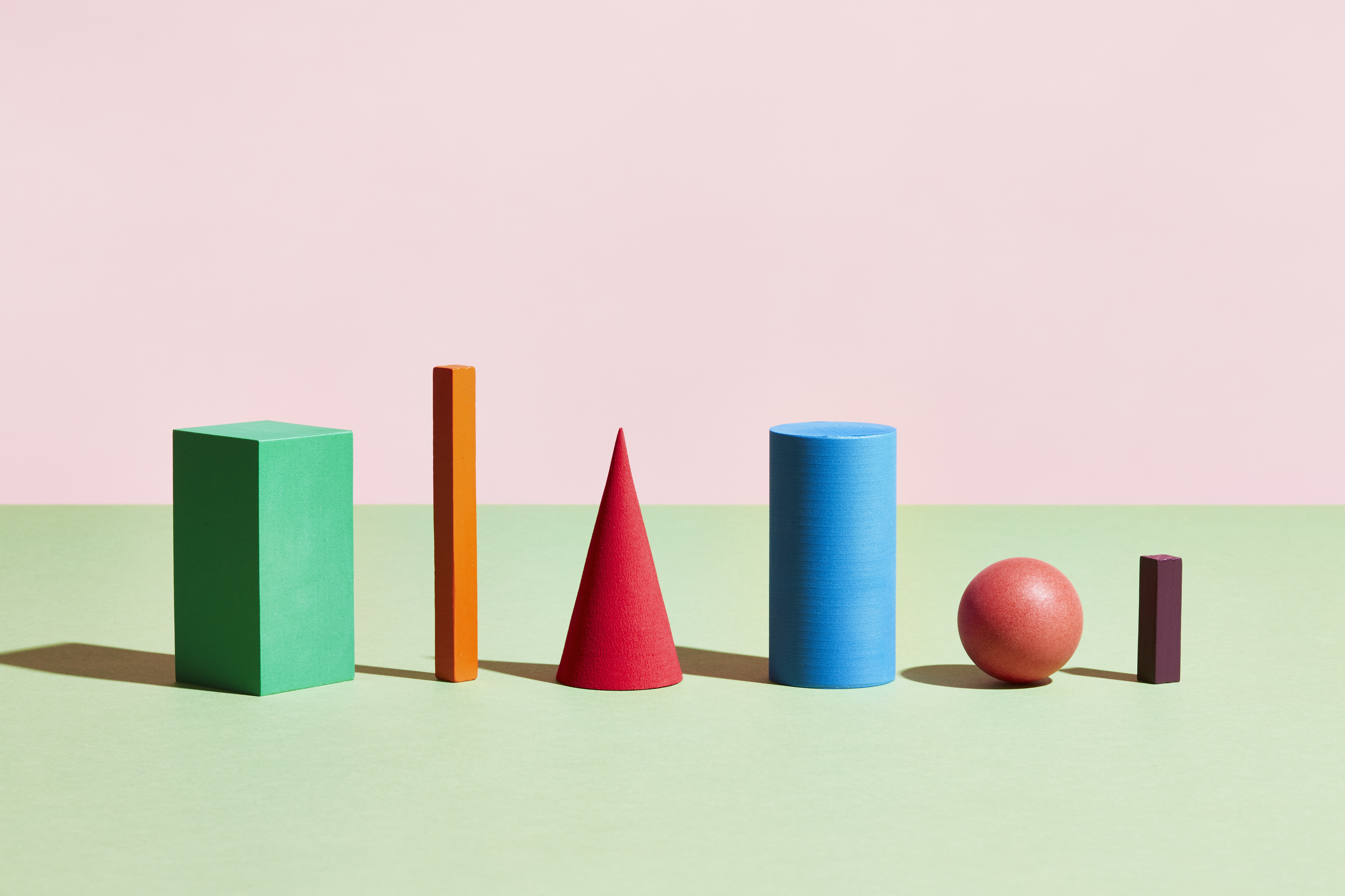 A line of wooden shapes, two cuboids, a cone, a cylinder, and a sphere