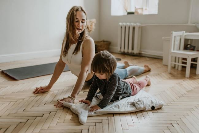 Vrouw doet yoga oefening met kind er naast