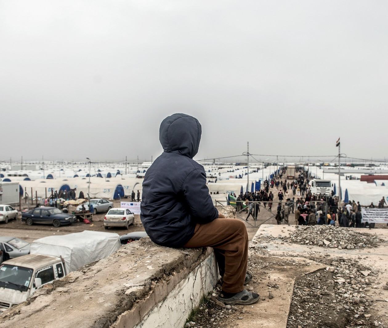 A boy looks out over Hamam Alil displaced peoples camp in Iraq. Photo: IFRC/Tommy Trenchard/Panos Pictures