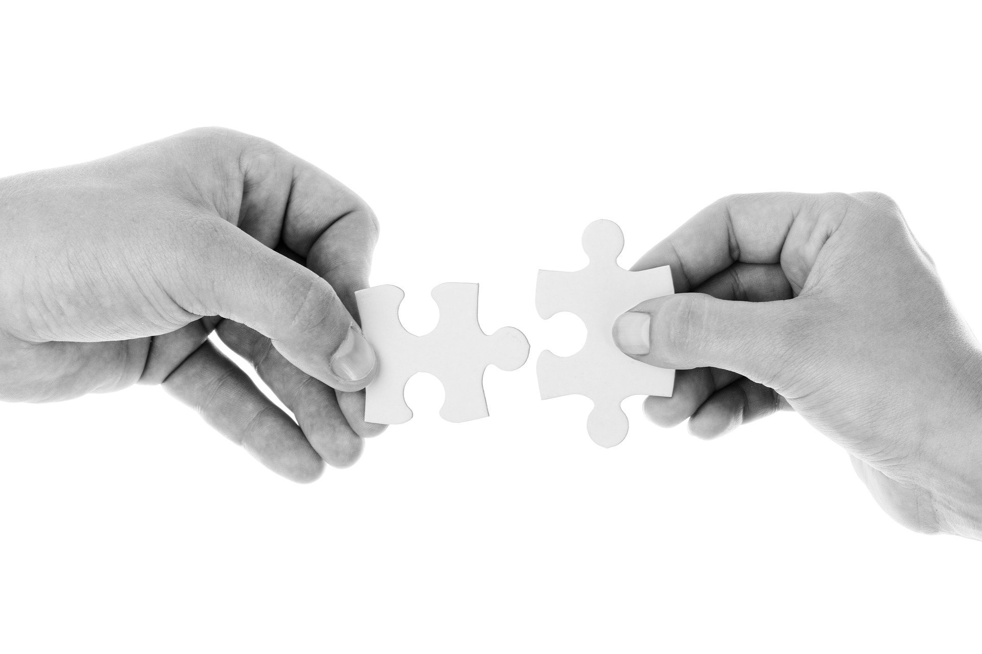 two hands connecting jigsaw pieces in black and white