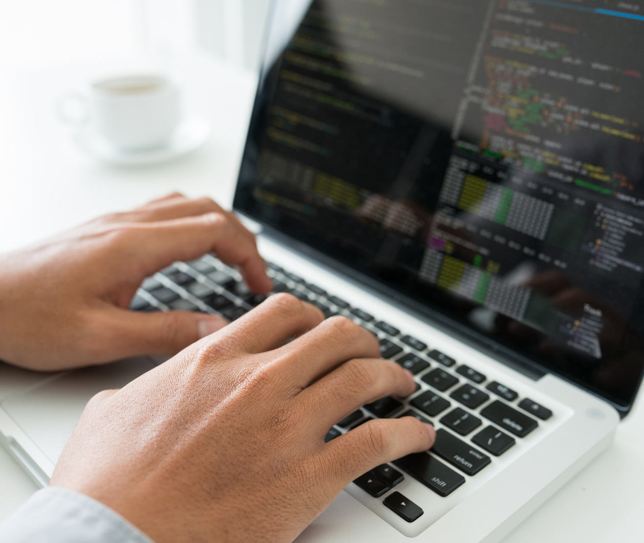 Hands coding on a laptop.