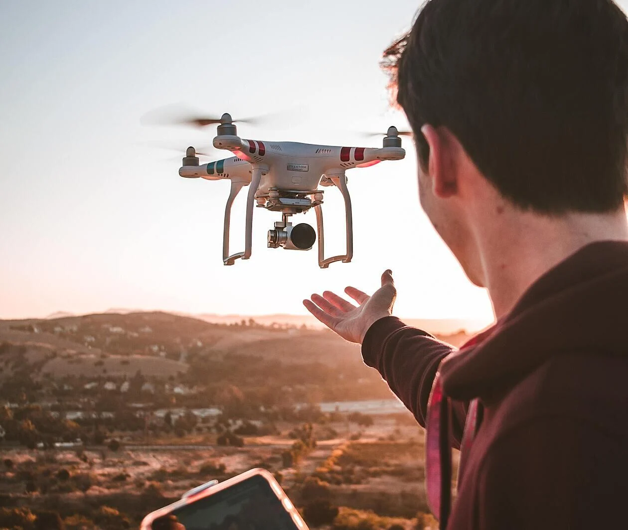 a man flying a drone at sunset