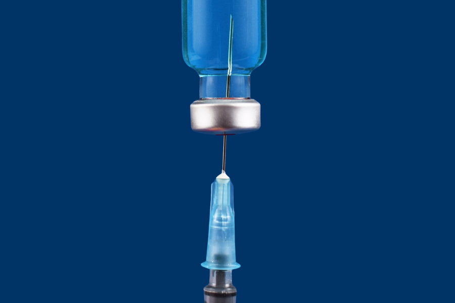 A syringe with needle drawing from a vial of liquid medication.