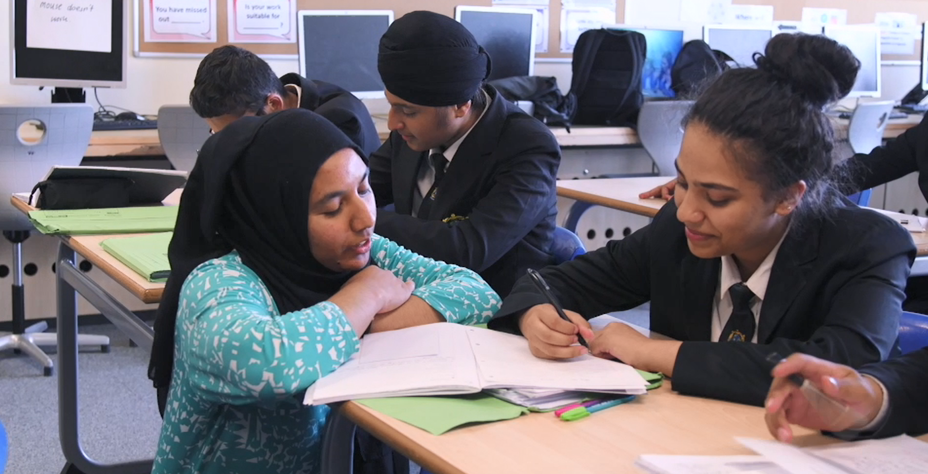 Teacher explaining work to a pupil at her desk