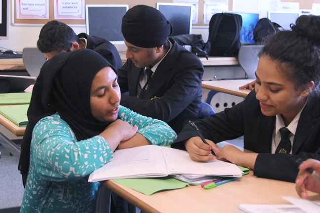 Teacher explaining work to a pupil at her desk