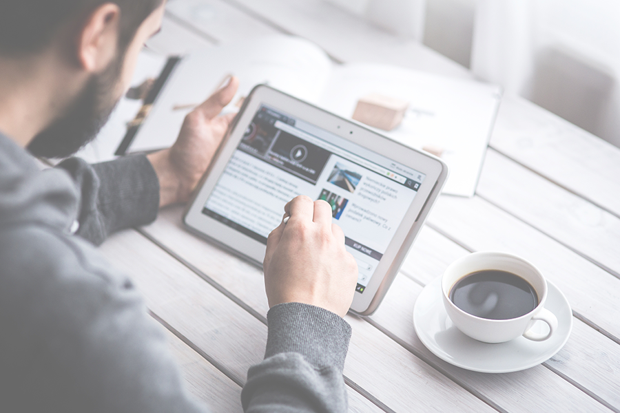 Photo of man reading the news on a tablet