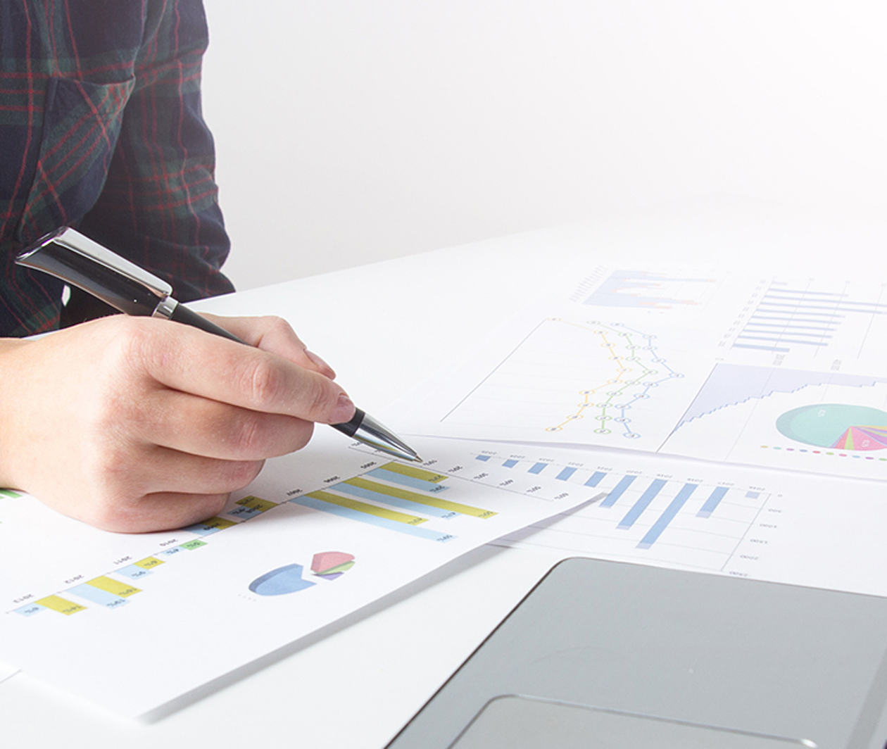 Two people discussing papers with images of graphs next to a laptop