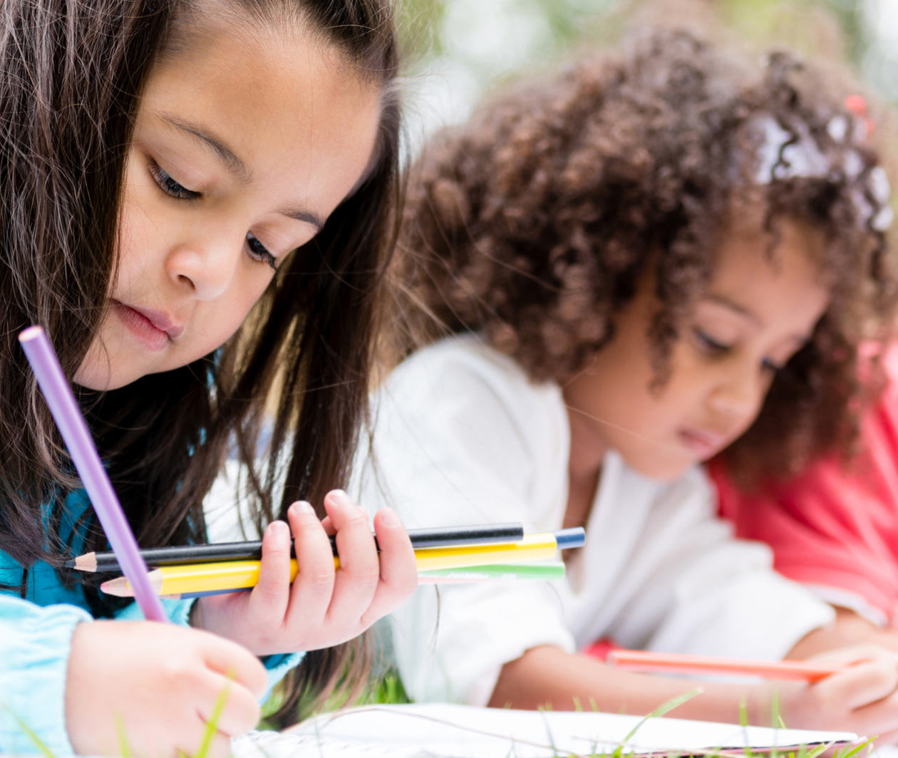 Inclusive education: a diverse group of children lie on grass completing school work