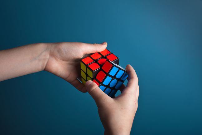 Two hands holding a Rubik's cube puzzle that's about to be solved.