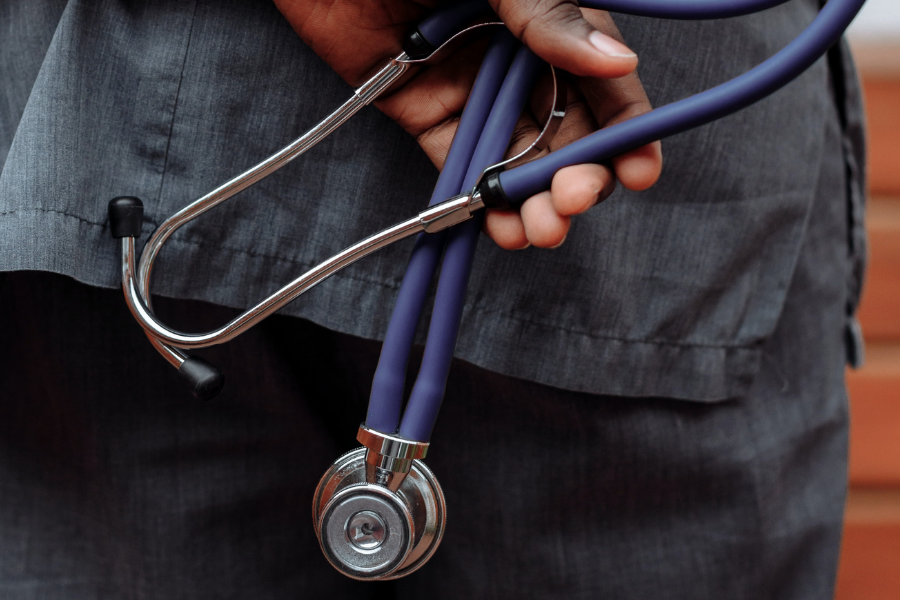 Image of doctor holding a blue stethoscope behind his back