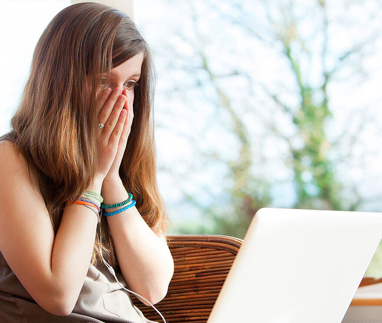 A woman appears shocked whilst on a laptop.