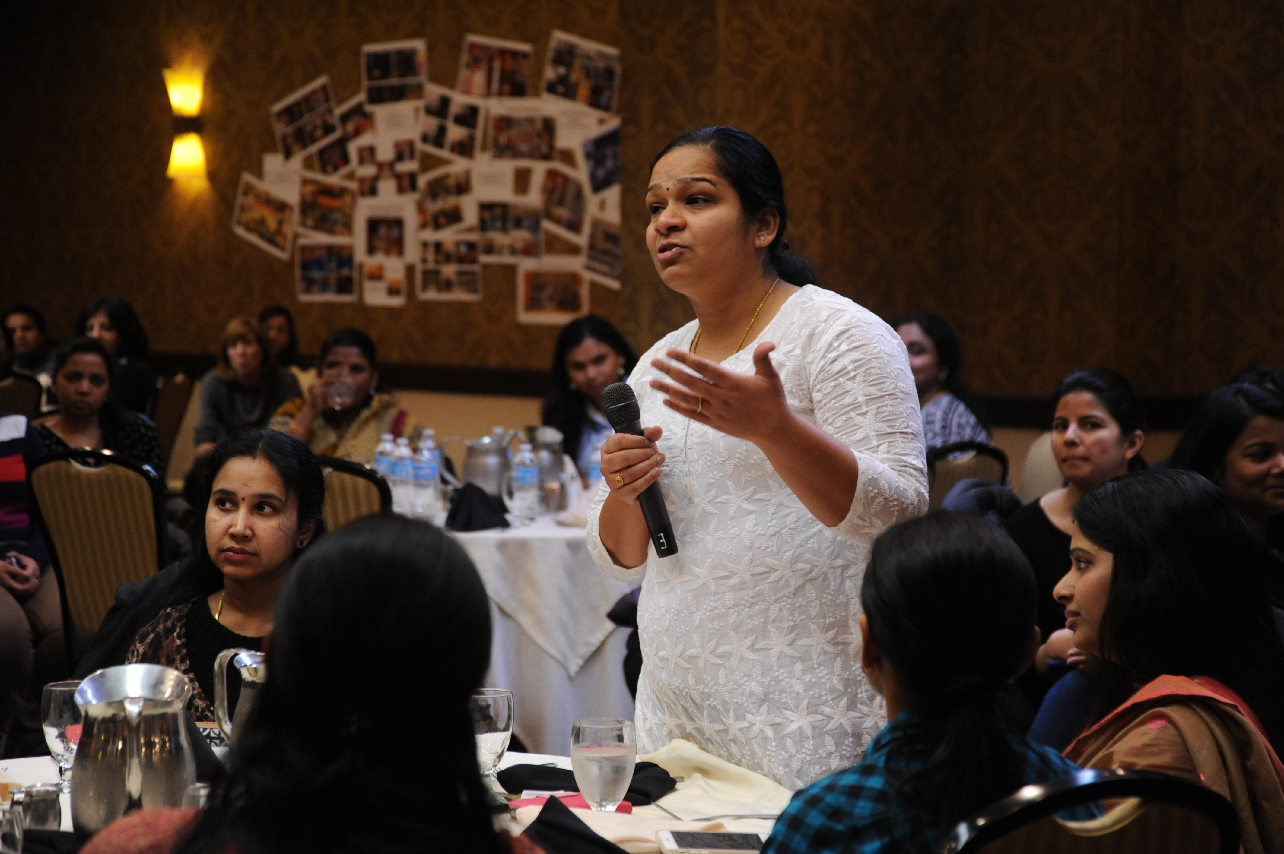 woman with microphone speaking to a crowded room