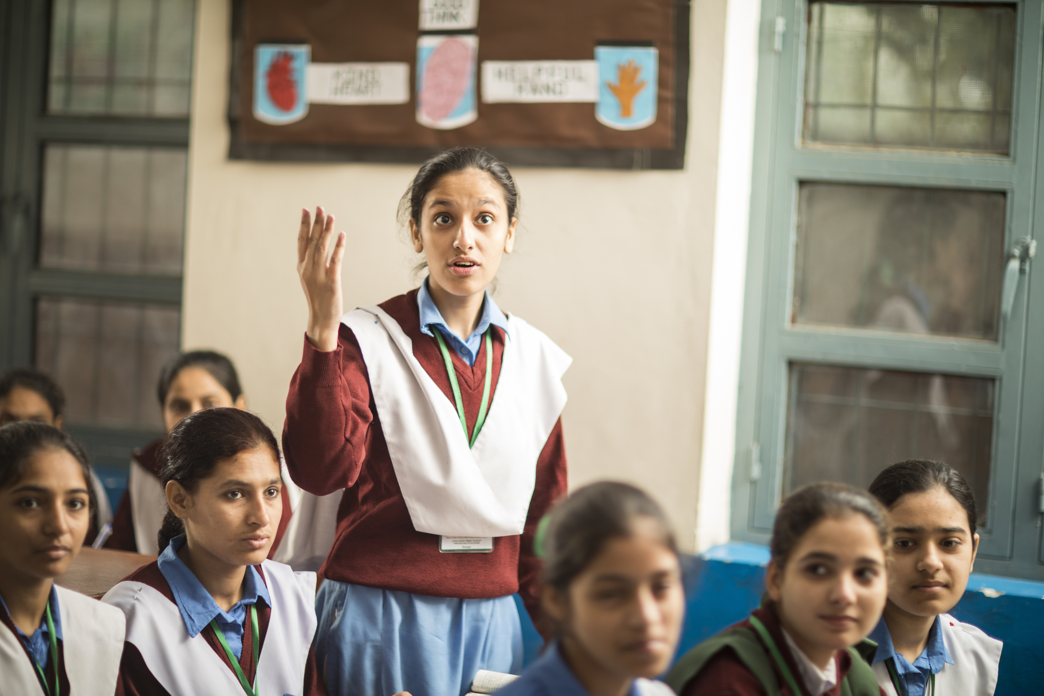 A student raising her hand in a classroom