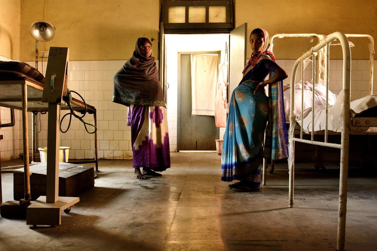 Two expectant mothers stand facing each other in a hospital room