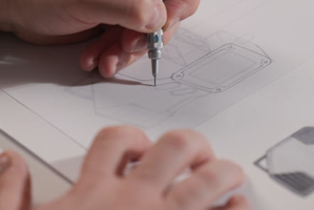 Educator shown sketching a 3D representation of a communications device with a mechanical pencil