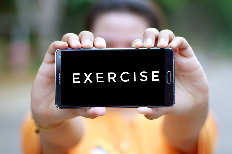 Person holding a mobile phone showing the word exercise