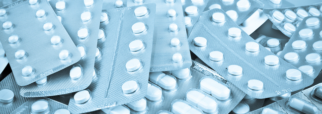 A pile of various pill packets, representing drugs and medicines