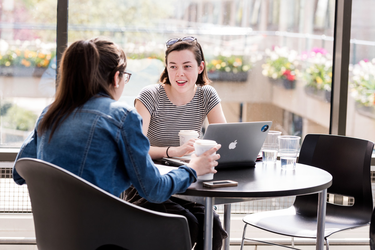 two girls talking drinking coffee