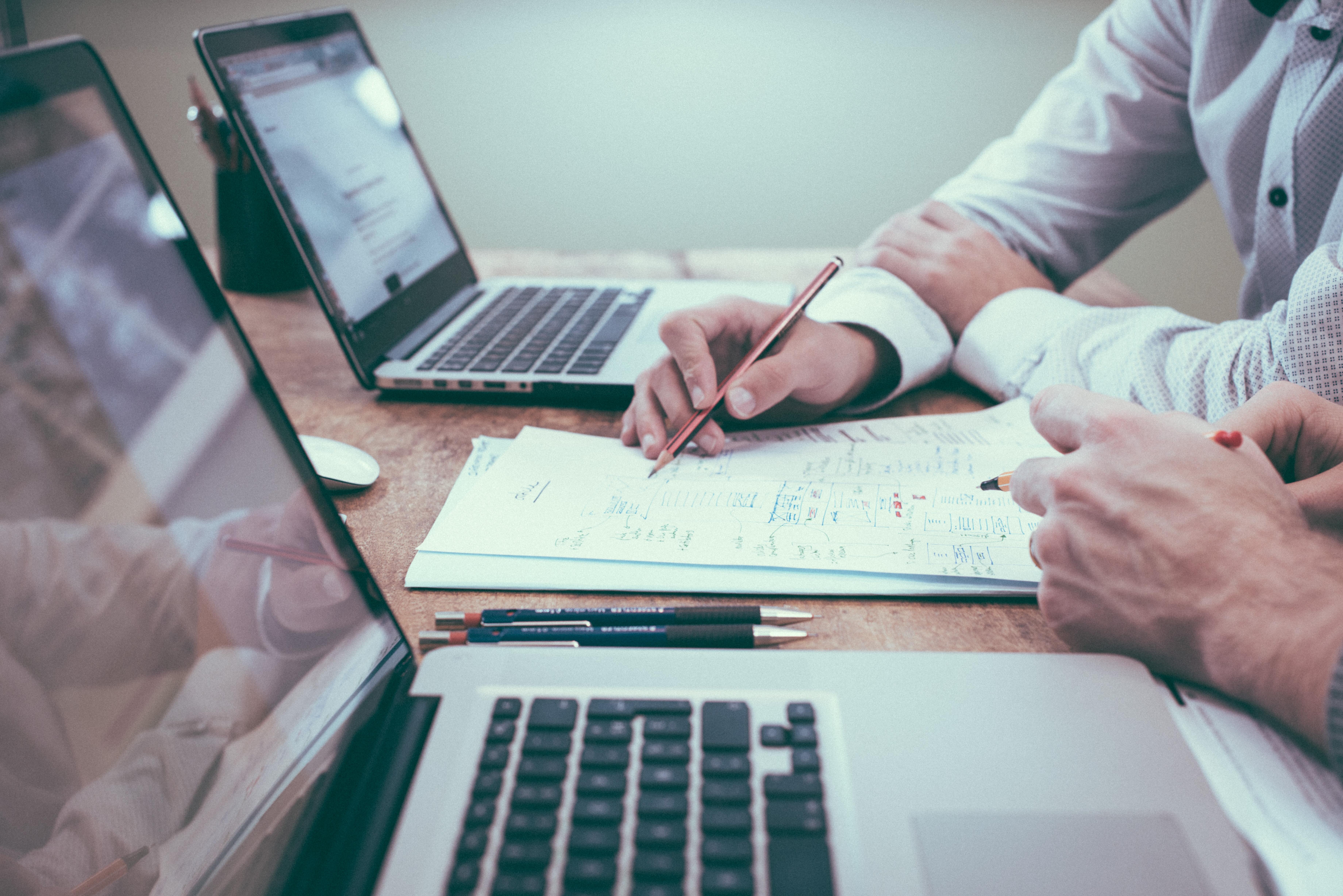 Sharing learning with two people on laptops next to each other writing notes (Source unsplash.com homajob)