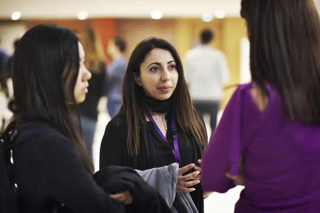 Three learners talking together and standing facing each other