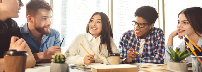 Diverse group of students round a table studying together