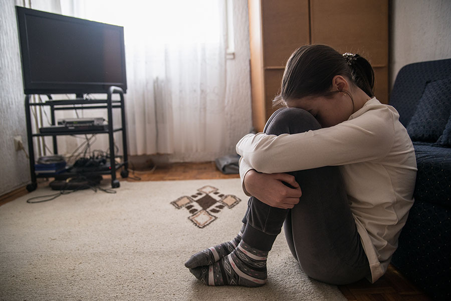 Young girl sits with head on her knees