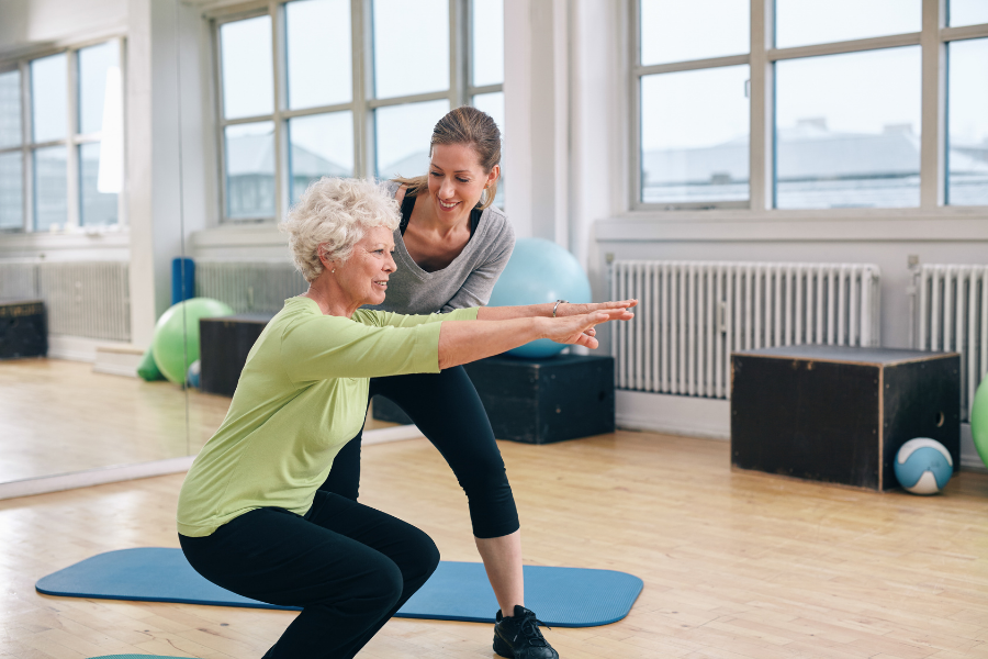 older lady squats with personal trainer