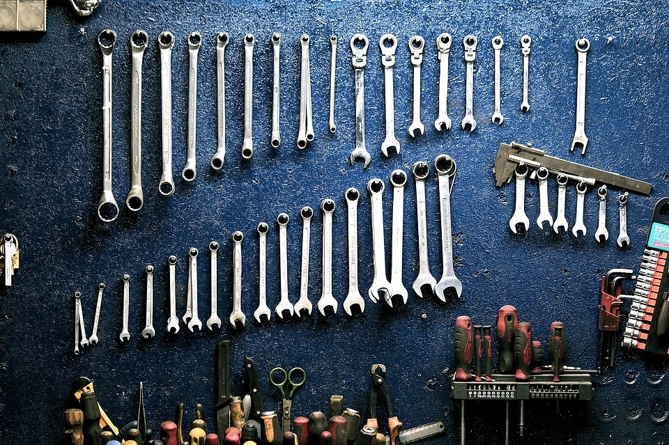 A collection of mechanical tools, including spanners, hanging up in a workshop.