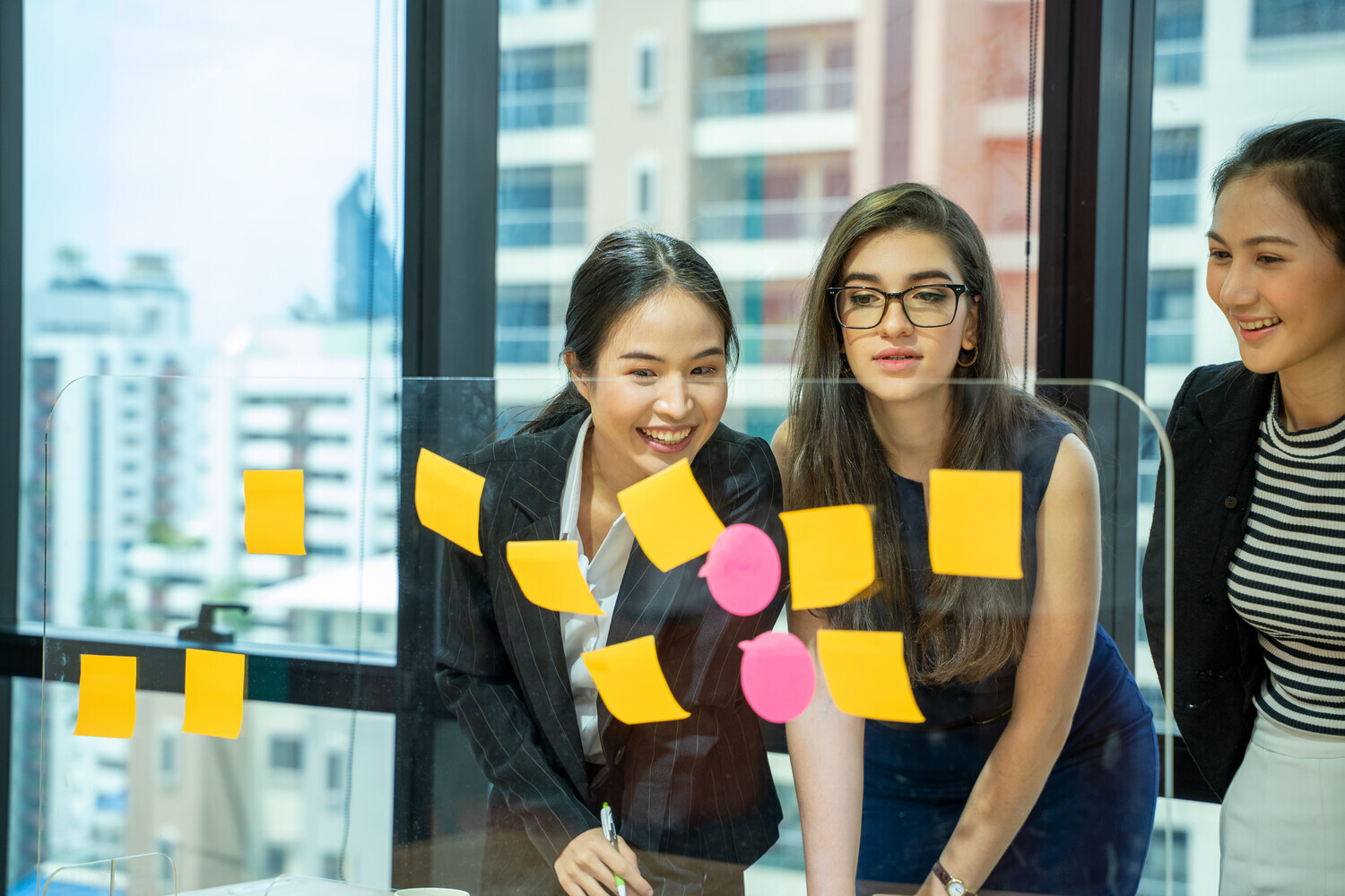 Image of three students sticking post it notes up